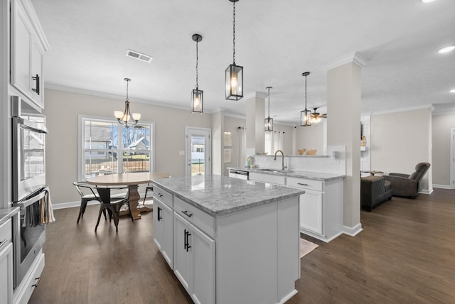 kitchen featuring a center island, crown molding, dark wood-style floors, stainless steel double oven, and a sink