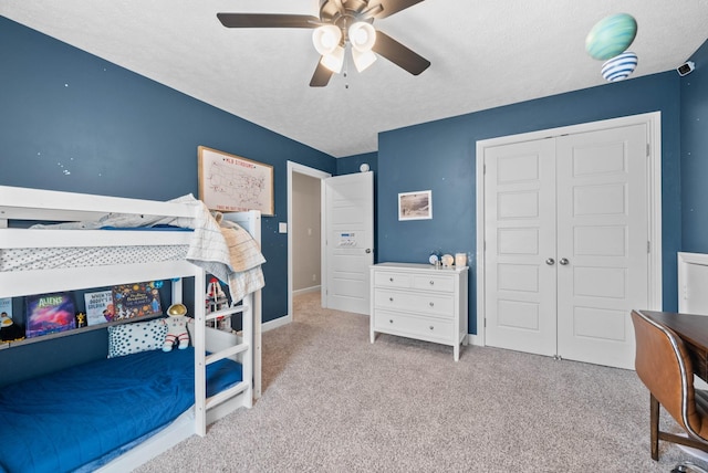 carpeted bedroom with a closet, baseboards, a textured ceiling, and a ceiling fan