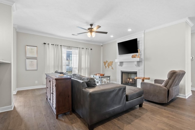 living room with a large fireplace, wood finished floors, a ceiling fan, and ornamental molding