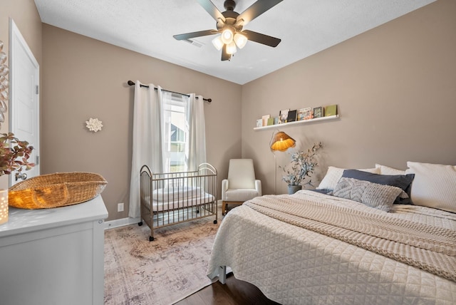 bedroom featuring a ceiling fan, wood finished floors, visible vents, and baseboards