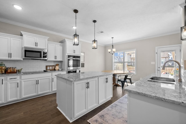 kitchen featuring dark wood-type flooring, a sink, backsplash, a center island, and appliances with stainless steel finishes