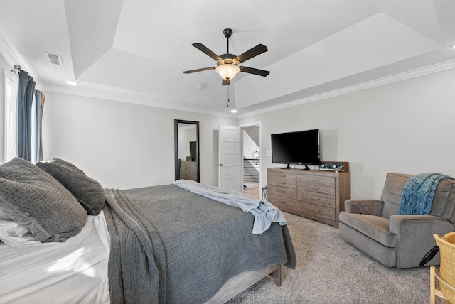 bedroom featuring a tray ceiling, light colored carpet, visible vents, and crown molding