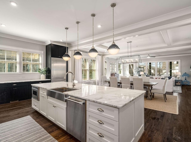 kitchen featuring a sink, appliances with stainless steel finishes, dark wood-style floors, and an island with sink