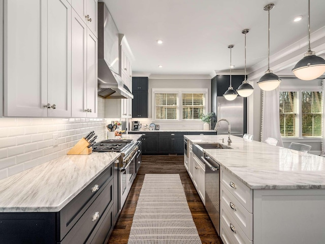 kitchen with tasteful backsplash, a large island with sink, wall chimney exhaust hood, high end appliances, and a sink