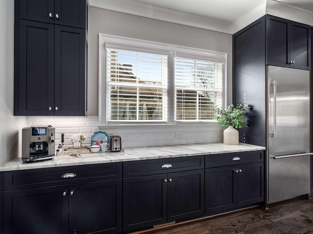 kitchen with backsplash, light stone counters, and high quality fridge