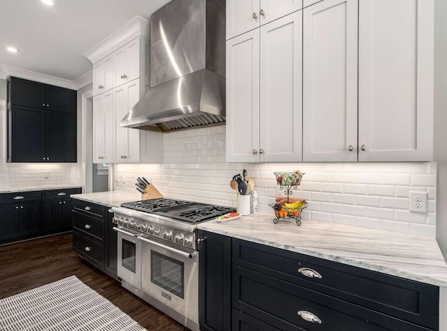 kitchen with wall chimney range hood, dark cabinets, and range with two ovens