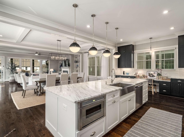 kitchen with dark wood-type flooring, a kitchen island with sink, appliances with stainless steel finishes, and a sink