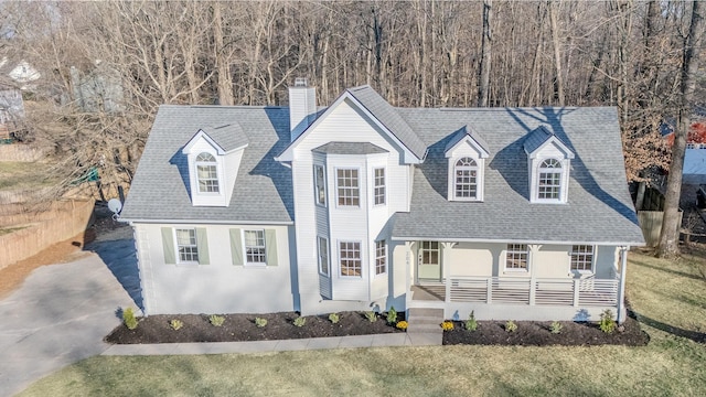 cape cod-style house with covered porch, a chimney, a front lawn, and a shingled roof