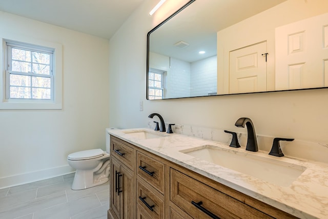 bathroom with toilet, a wealth of natural light, and a sink