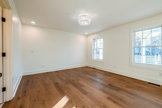 unfurnished room featuring baseboards, visible vents, and wood-type flooring