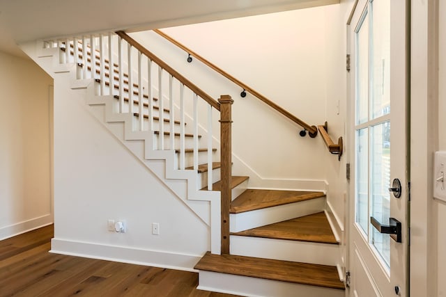 staircase featuring wood finished floors and baseboards