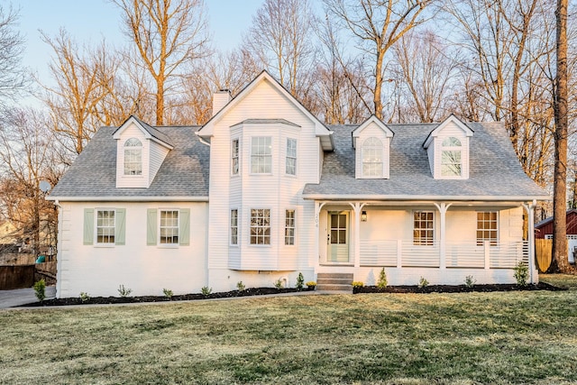 view of front of home featuring a shingled roof, a porch, a front yard, and a chimney