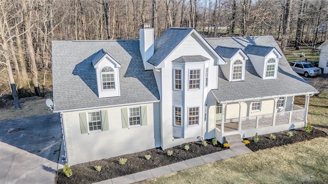 cape cod home featuring covered porch, roof with shingles, and a chimney