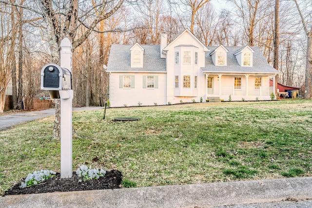 view of front of property featuring a chimney, a front lawn, and a shingled roof