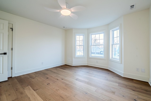 spare room with visible vents, ceiling fan, baseboards, and wood finished floors