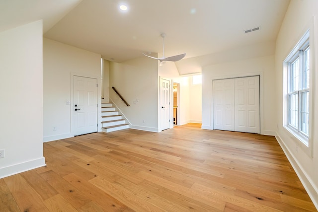 interior space featuring light wood-type flooring, visible vents, stairway, baseboards, and vaulted ceiling