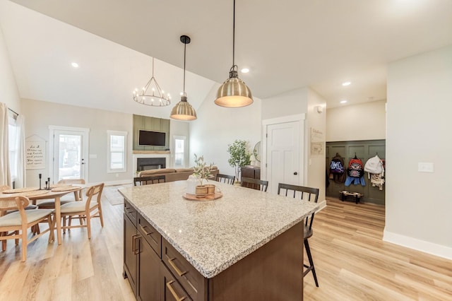 kitchen with light wood finished floors, a center island, a breakfast bar, and a large fireplace