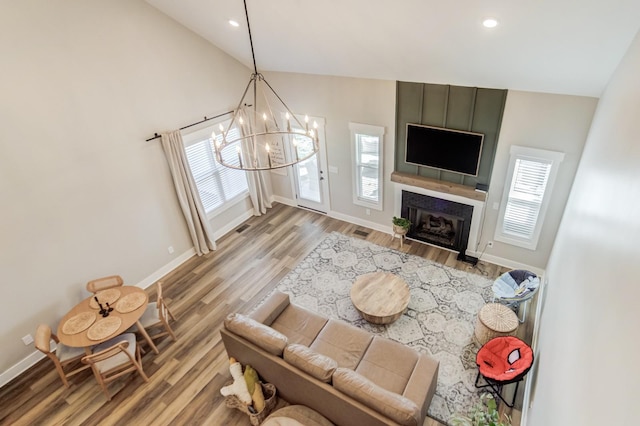 living area featuring light wood-style flooring, an inviting chandelier, a healthy amount of sunlight, and vaulted ceiling