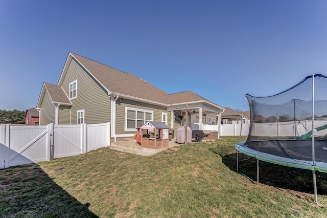 rear view of property with a lawn, a gate, a patio, a trampoline, and a fenced backyard