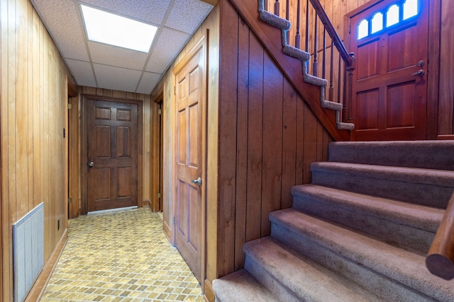 interior space featuring wooden walls, a paneled ceiling, and visible vents