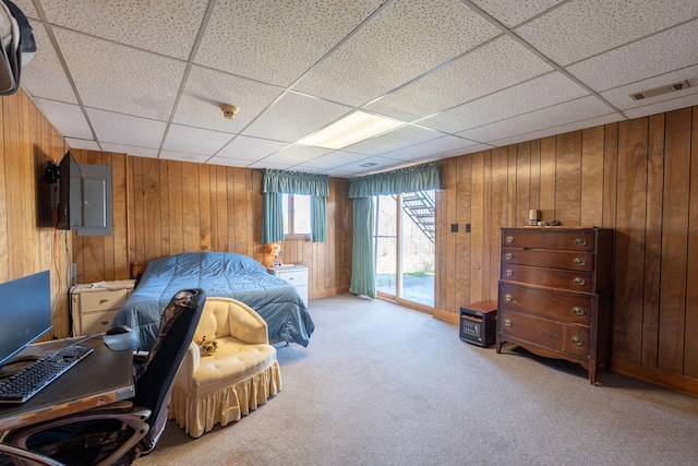 bedroom with access to exterior, visible vents, carpet, a drop ceiling, and wood walls