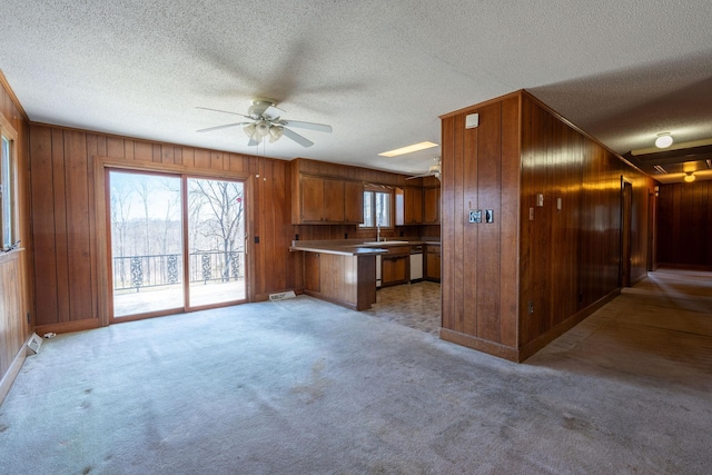 kitchen featuring light colored carpet, a peninsula, brown cabinets, and ceiling fan