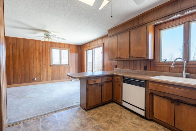 kitchen featuring brown cabinets, a sink, a peninsula, white dishwasher, and ceiling fan