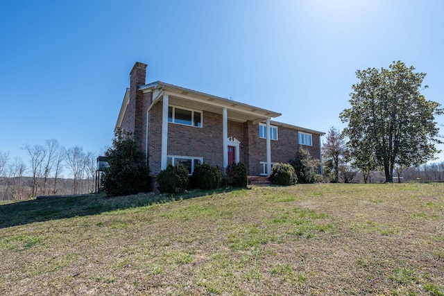 bi-level home with brick siding, a chimney, and a front yard