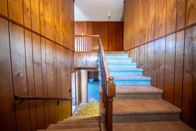 stairway featuring wood walls