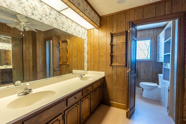 bathroom with a sink, toilet, ceiling fan, and wood walls