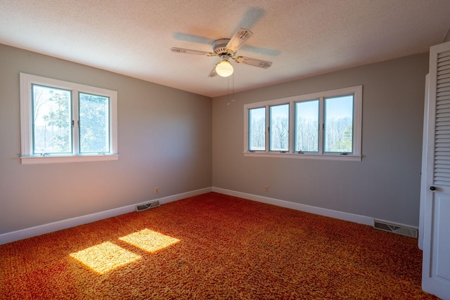 carpeted spare room with visible vents, baseboards, a textured ceiling, and a ceiling fan