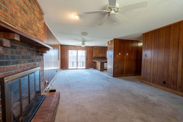 unfurnished living room with light carpet, a textured ceiling, ceiling fan, and wood walls