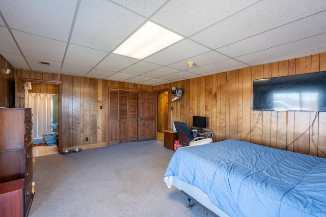 carpeted bedroom featuring visible vents, a paneled ceiling, and wooden walls