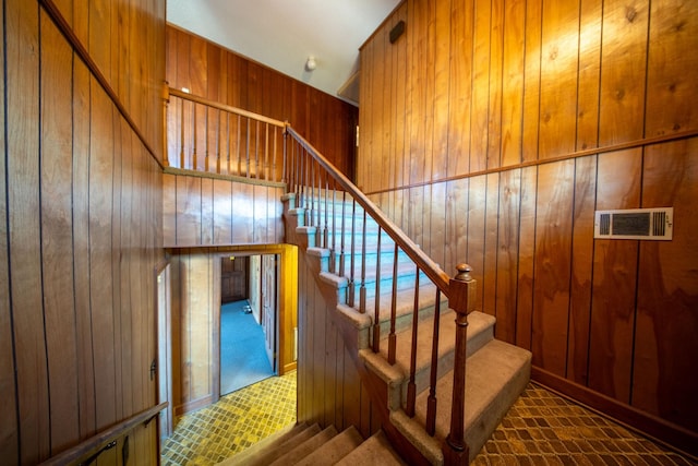 stairs featuring visible vents, wood walls, and carpet