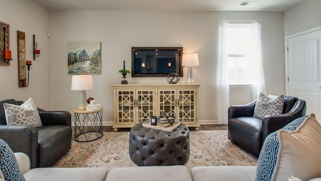 living area with visible vents, baseboards, and wood finished floors