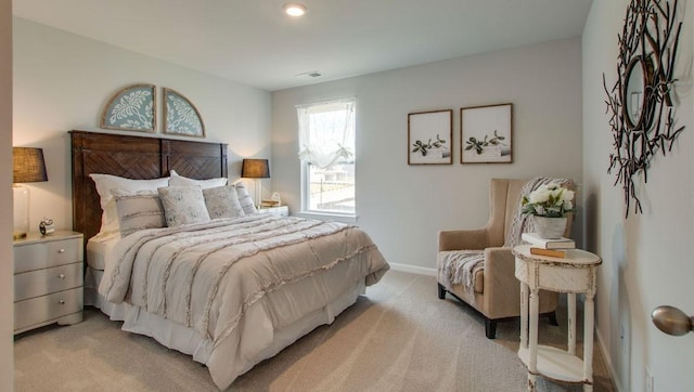 bedroom featuring visible vents, light colored carpet, and baseboards