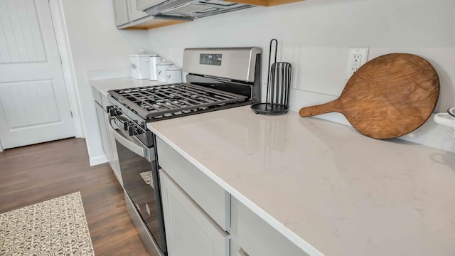 kitchen featuring stainless steel gas range oven, light stone counters, extractor fan, and dark wood-style flooring