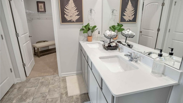 bathroom featuring a sink, a walk in closet, baseboards, and double vanity