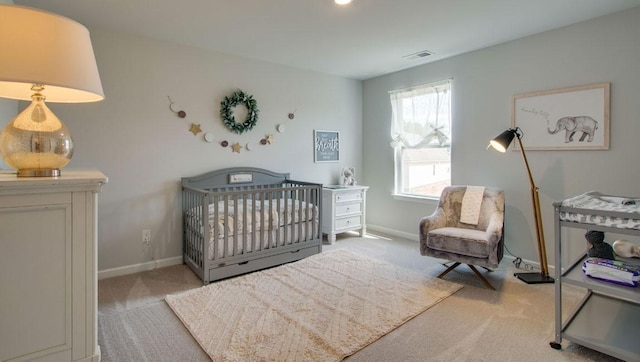 carpeted bedroom with a crib, baseboards, and visible vents