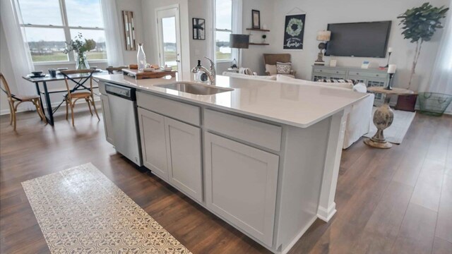 kitchen featuring a sink, open floor plan, light countertops, dark wood-style floors, and stainless steel dishwasher