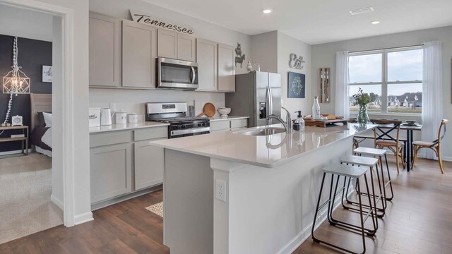 kitchen with visible vents, a center island with sink, a sink, a kitchen breakfast bar, and appliances with stainless steel finishes