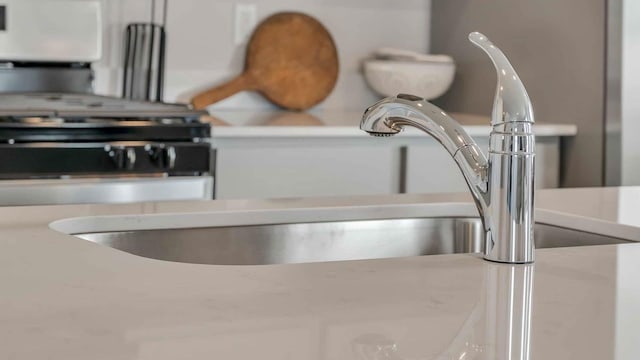 interior details with a sink, white cabinetry, and light countertops