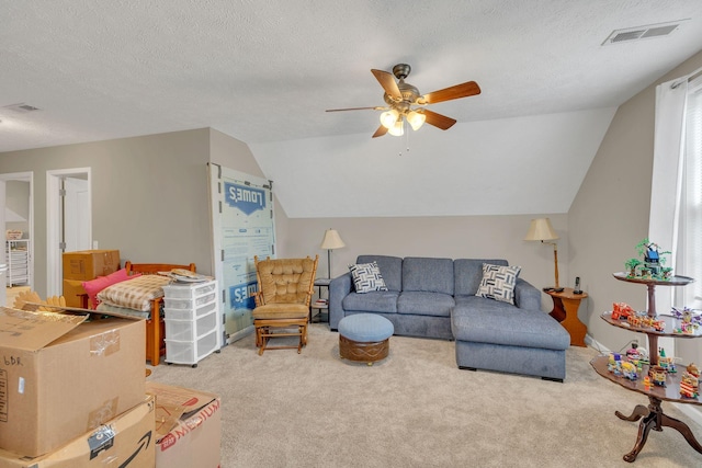 carpeted living area with visible vents, a textured ceiling, a ceiling fan, and vaulted ceiling