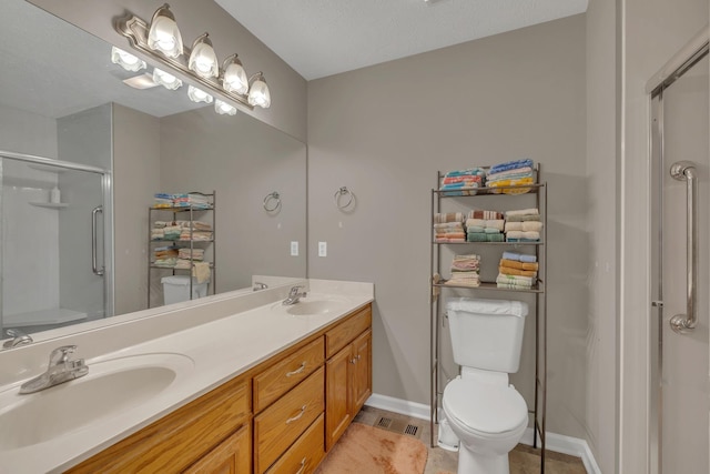 bathroom featuring double vanity, a stall shower, toilet, and a sink