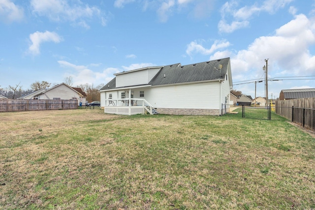 rear view of house featuring roof with shingles, a lawn, a deck, a fenced backyard, and a gate