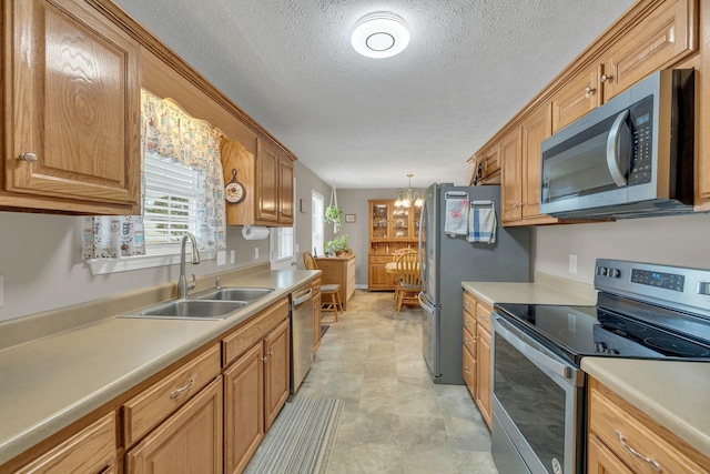 kitchen featuring a sink, a textured ceiling, appliances with stainless steel finishes, and light countertops