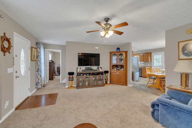 living room with light carpet, baseboards, and ceiling fan