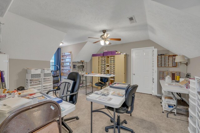 carpeted office space featuring visible vents, a textured ceiling, a ceiling fan, and vaulted ceiling