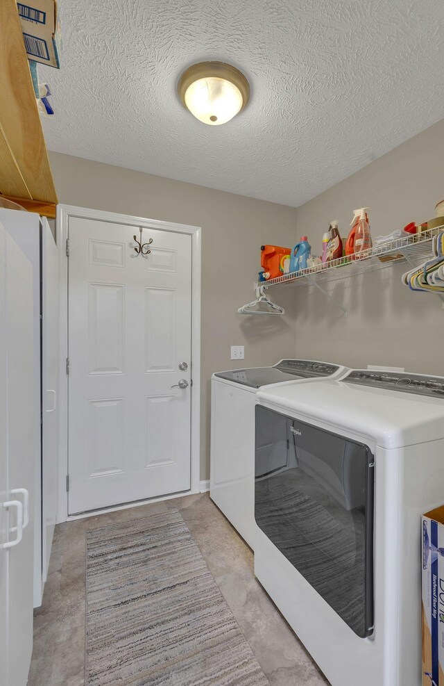washroom featuring a textured ceiling, washing machine and dryer, and laundry area