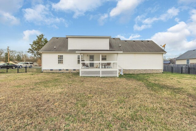 back of house with crawl space, a lawn, a shingled roof, and fence